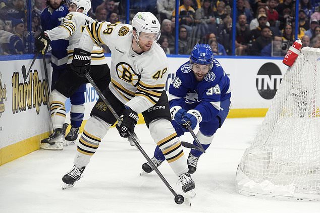 Boston Bruins defenseman Matt Grzelcyk (48) moves the puck ahead of Tampa Bay Lightning left wing Brandon Hagel (38) during the second period of an NHL hockey game Wednesday, March 27, 2024, in Tampa, Fla. (AP Photo/Chris O'Meara)