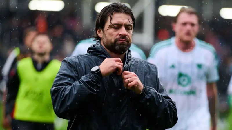 Leicester manager Russell Martin, wearing a dark anorak, looks dejected as he walks off the pitch at Luton
