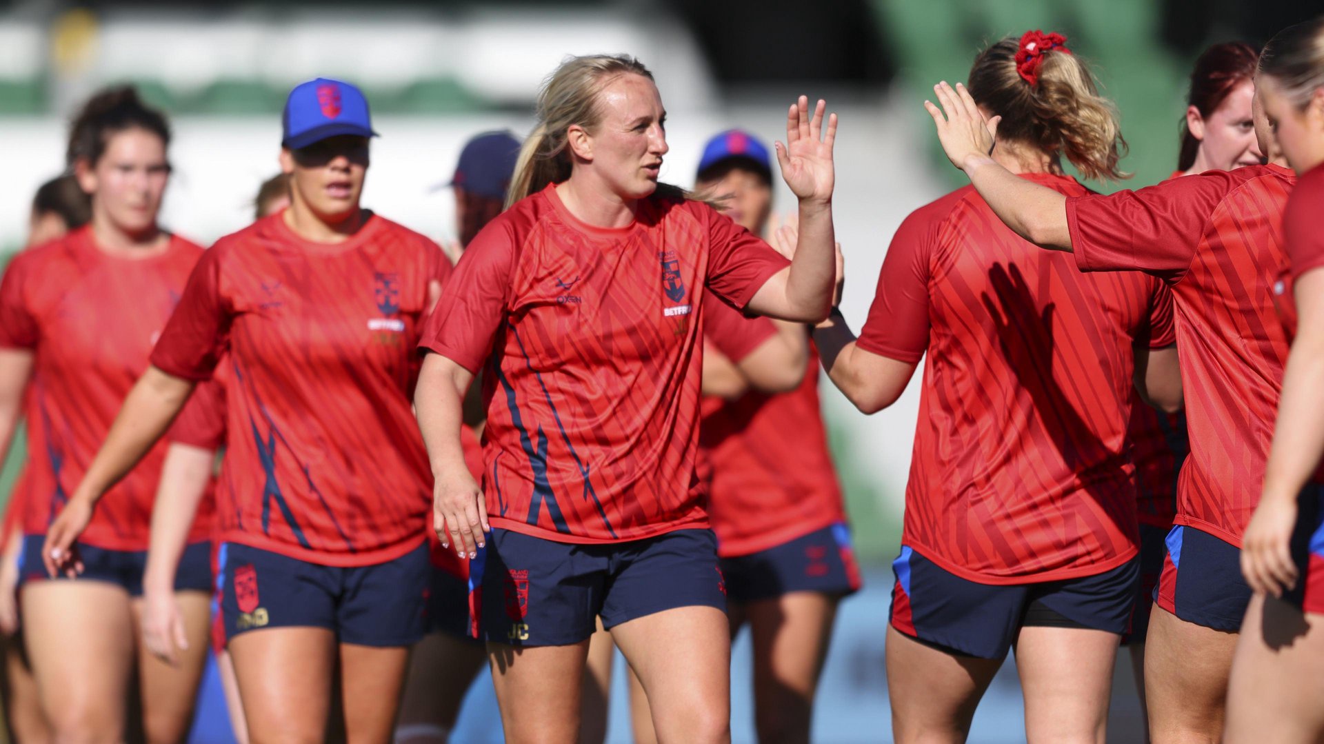 Jodie Cunningham, wearing a red T-shirt, gives a high-five to a team-mate