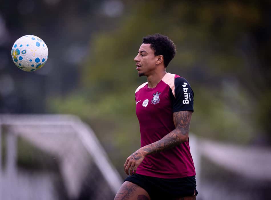 Jesse Lingard durante treino, observando bola no ar, com camisa vinho e shorts pretos.