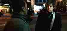 Don Cheadle and Adam Sandler in a scene, standing on a street at night, engaged in conversation