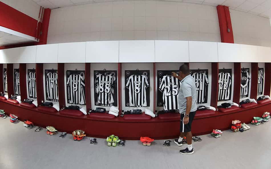 Homem observa camisas pretas e brancas de Inter x Botafogo penduradas no vestiário.