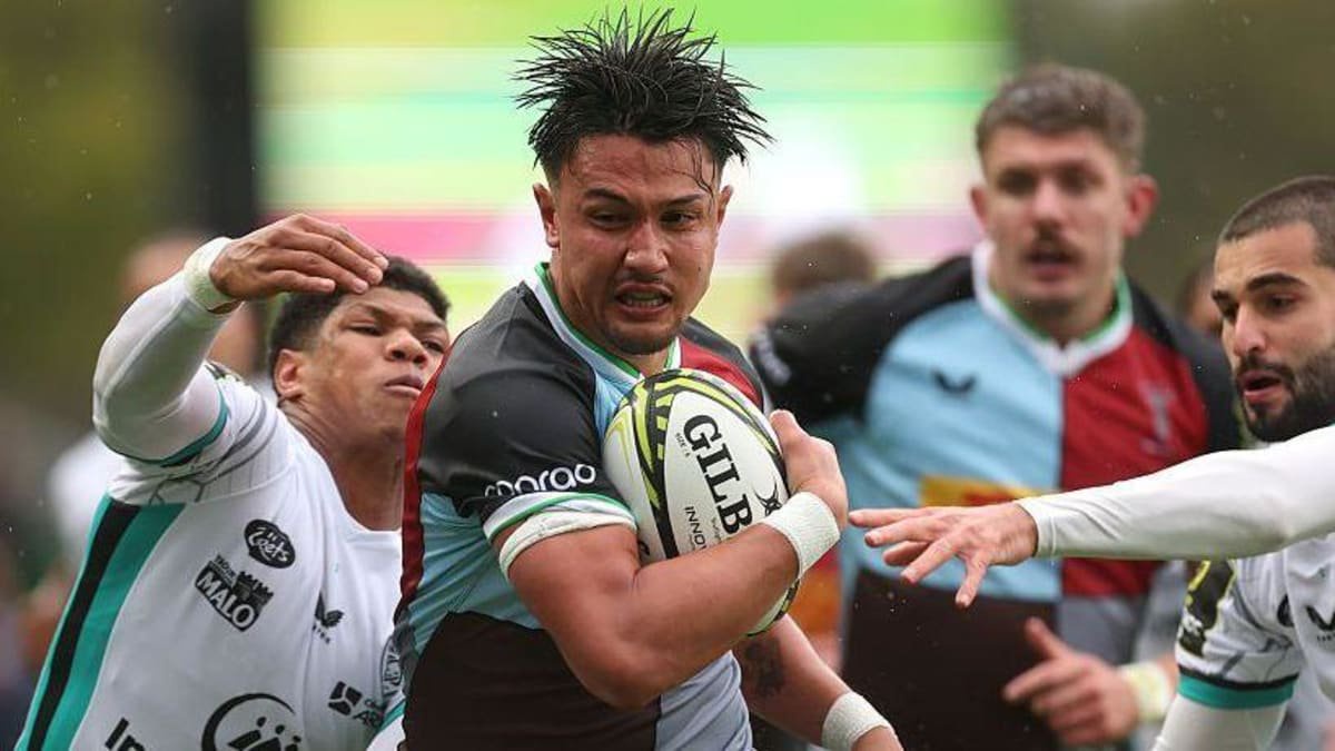 Marcus Smith (centre) has the ball in his right hand/arm as two Vannes players reach out with their hands to try to stop him