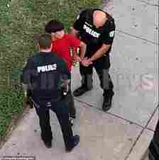 Drone footage captured a young man wearing a red t-shirt and black pants being arrested after he was filmed him handing off what appears to be drugs through the passenger side of a black sedan