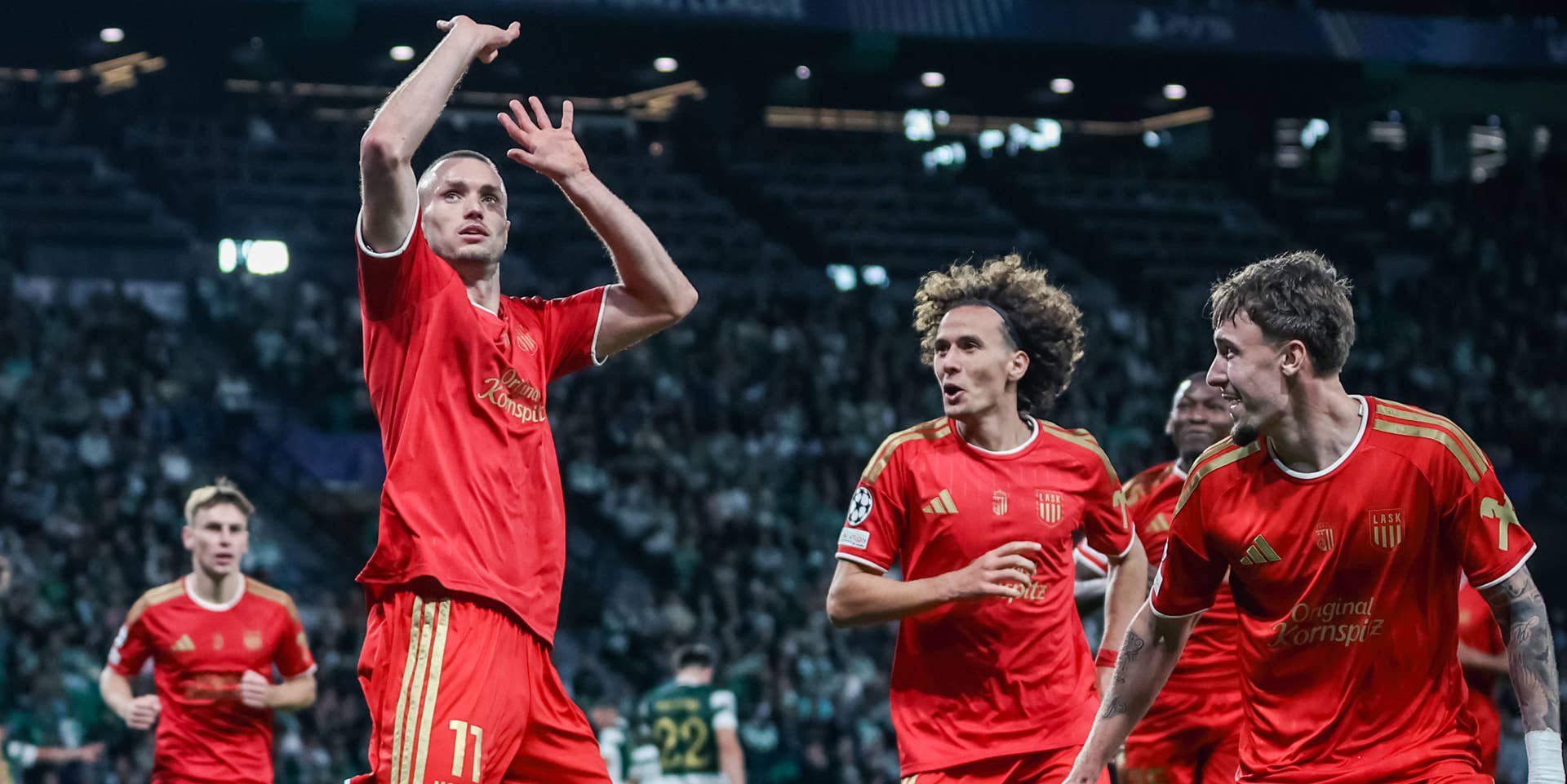 LASK-Spieler jubeln im roten Trikot während eines UEFA-Champions-League-Spiels.