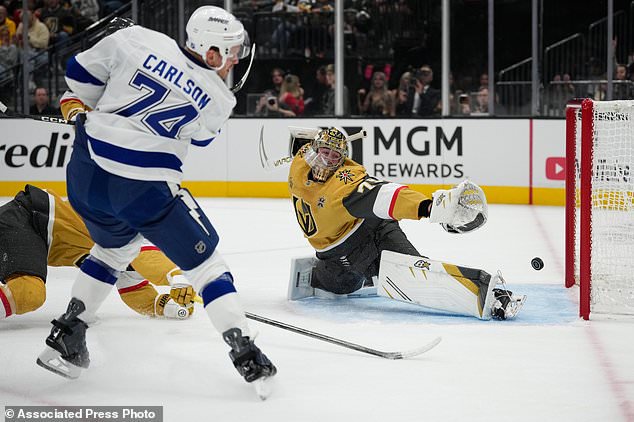 Tampa Bay Lightning defenseman John Carlson (74) scores against Vegas Golden Knights goaltender Carter Hart (79) during the first period of an NHL hockey game Tuesday, Oct. 20, 2026, in Las Vegas. (AP Photo/John Locher)