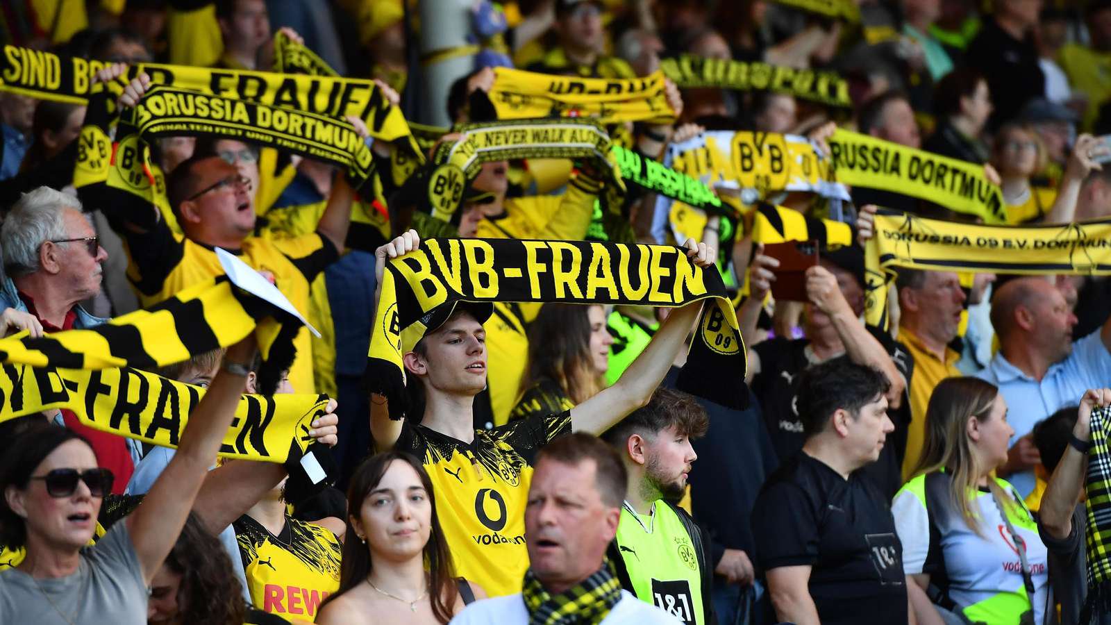 Fans der BVB-Frauen im Stadion Rote Erde halten ihre Schals in die Luft.