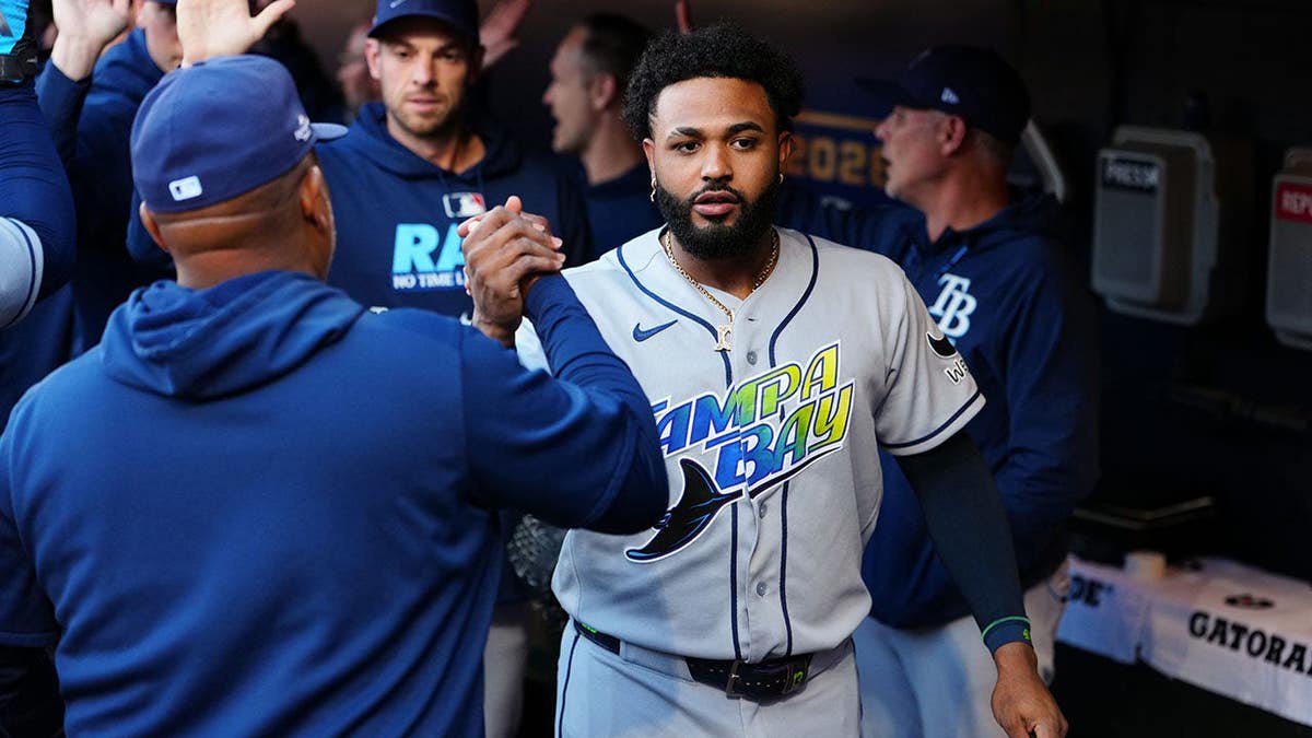 Junior Caminero celebrates with Ozzie Timmons in the dugout at Progressive Field.