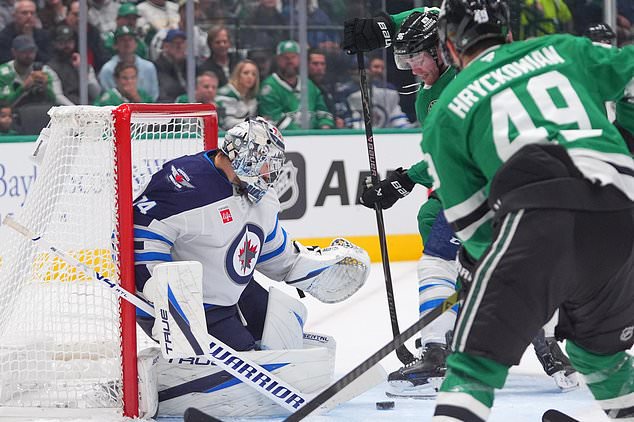 Winnipeg Jets goaltender Stuart Skinner (74) defends the goal against Dallas Stars right wing Mikko Rantanen (96) and center Justin Hryckowian (49) during the first period of an NHL hockey game Thursday, Oct. 22, 2026, in Dallas. (AP Photo/LM Otero)
