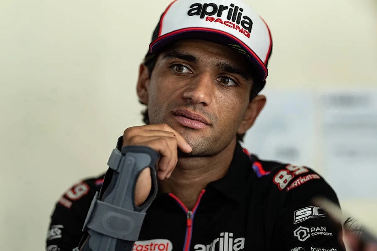Rider in black Aprilia Racing cap and team shirt holding a wrist brace at the paddock, Sepang MotoGP