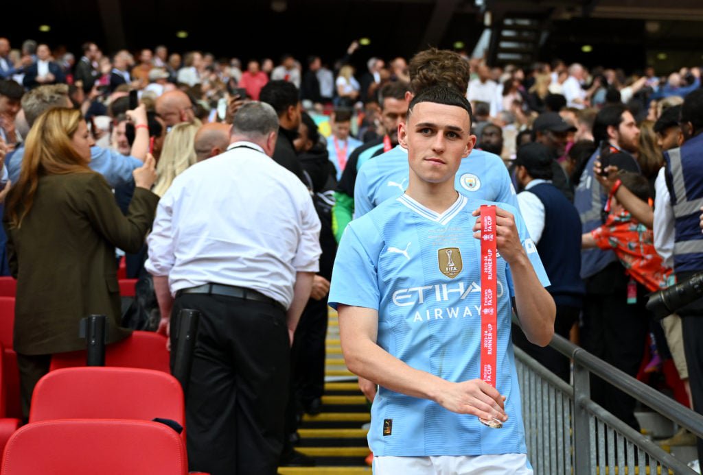 Phil Foden of Manchester City removes his runners up medal after the Emirates FA Cup Final match between Manchester City and Manchester United at W...