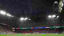 A bolt of lightning above a packed, floodlit football stadium