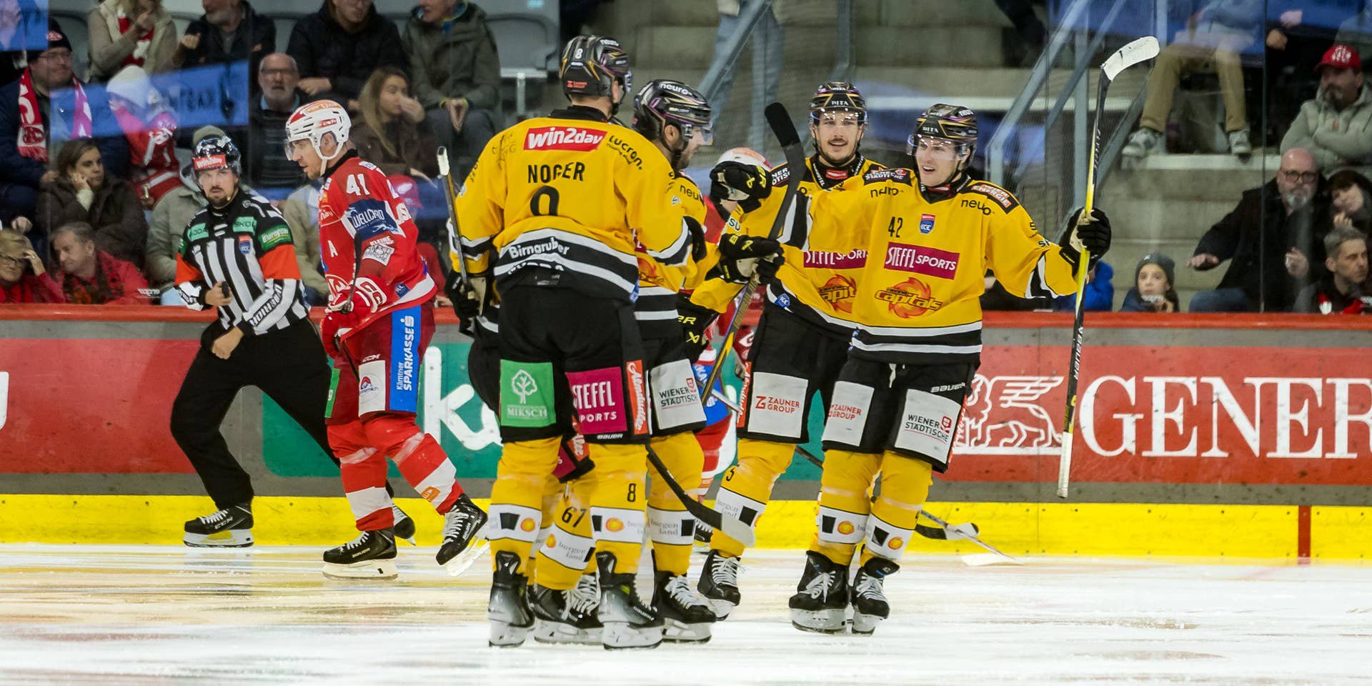 Die Spieler der Vienna Capitals jubeln in gelb-schwarzen Trikots auf dem Eis, während KAC-Akteure enttäuscht abdrehen.