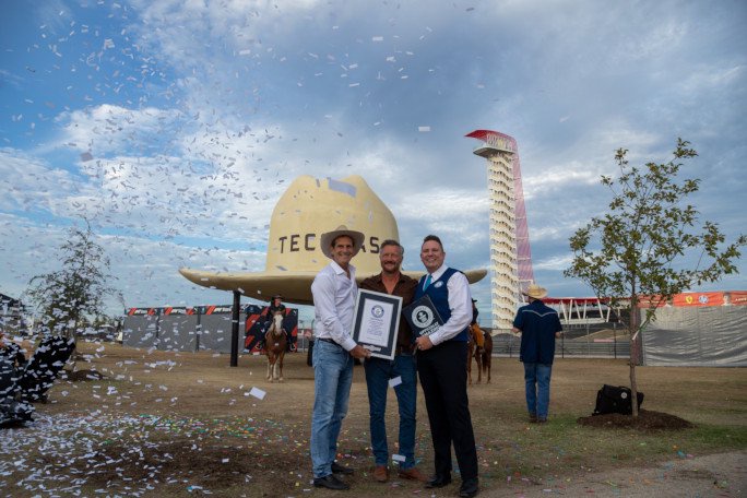 Adjudicator and organizers with certificate under the large hat and confetti