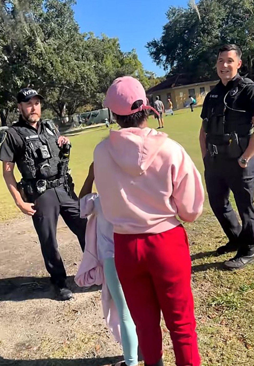 Police officers standing and talking with people at a youth soccer field.