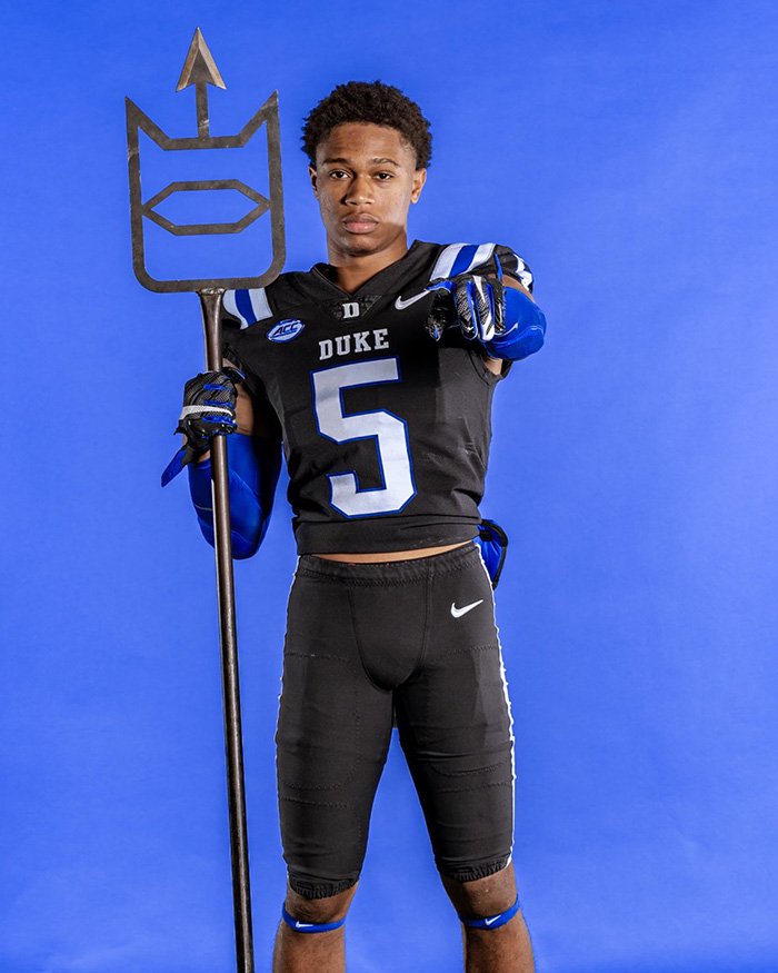 Star football player in Duke uniform holding a staff