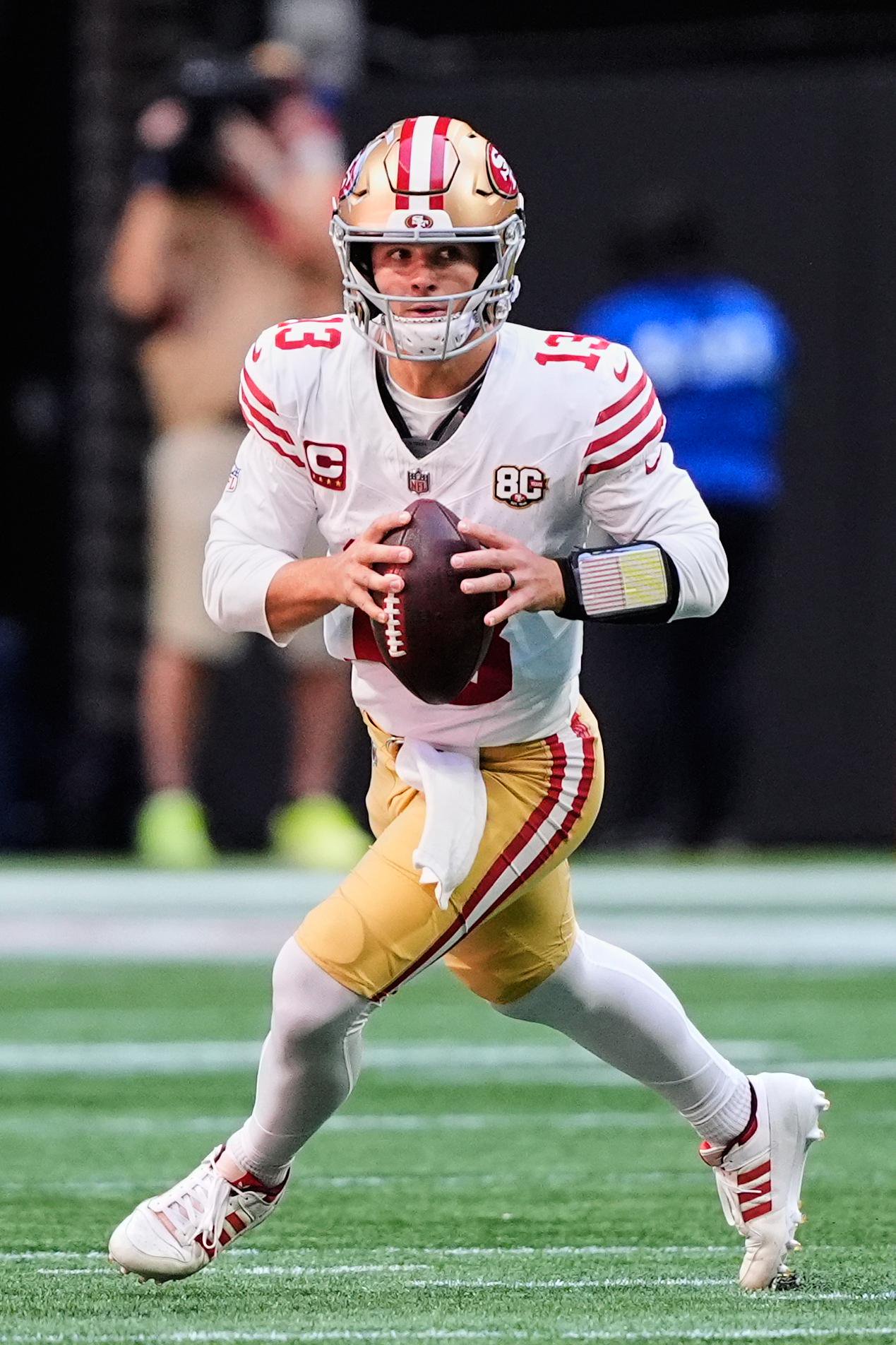 San Francisco 49ers quarterback Brock Purdy scrambles with the ball during a game.