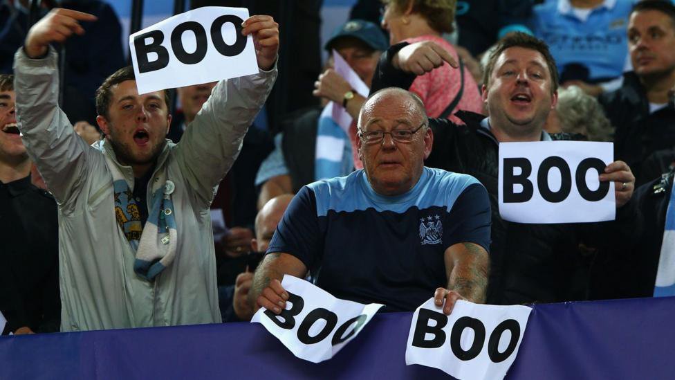 Manchester City fans holding signs reading 'BOO'