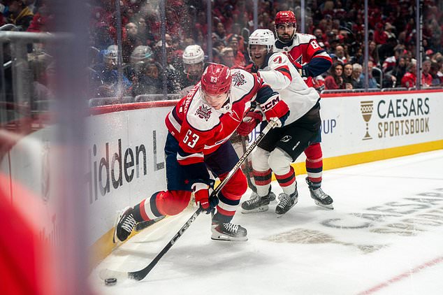 Washington Capitals left wing Ivan Miroshnichenko (63) and New Jersey Devils defenseman Dougie Hamilton (7) battle for the puck in the corner during the first period of an NHL hockey game against New Jersey Devils, Saturday, Oct. 17, 2026, in Washington. (AP Photo/Nathan Howard)