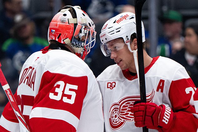 Detroit Red Wings goaltender Michal Postava (35) and Lucas Raymond (23) celebrate after defeating the Vancouver Canucks in an NHL hockey game in Vancouver, British Columbia, Thursday, Oct. 22, 2026. (Ethan Cairns/The Canadian Press via AP)