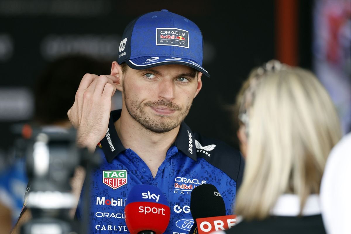 Max Verstappen with his hand to his ear as he speaks to TV stations in the media pen following the British Grand Prix