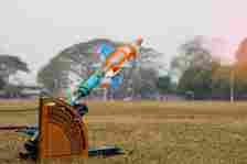 Plastic bottle water rocket, mounted on a wooden launcher, ready for takeoff in an open field with trees in the background