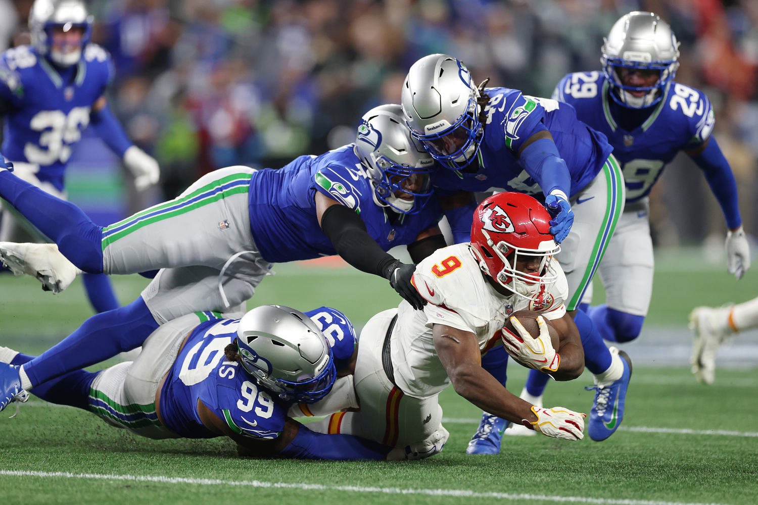 Chiefs running back Kenneth Walker III is tackled by Leonard Williams, Uchenna Nwosu and Tyrice Knight of the Seahawks. (Caleb Bowlin / Getty Images)