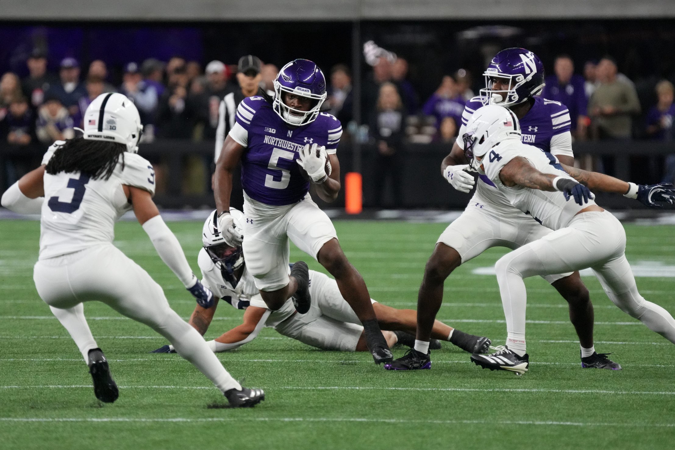 Oct 2, 2026; Evanston, Illinois, USA;  Northwestern Wildcats running back Caleb Komolafe (5) runs the ball against the Penn State Nittany Lions during the first quarter at New Ryan Field.  Mandatory Credit: David Banks-Imagn Images