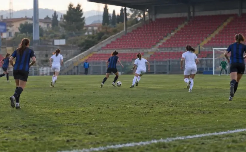 Women’s football match in an Italian stadium with players contesting the ball.