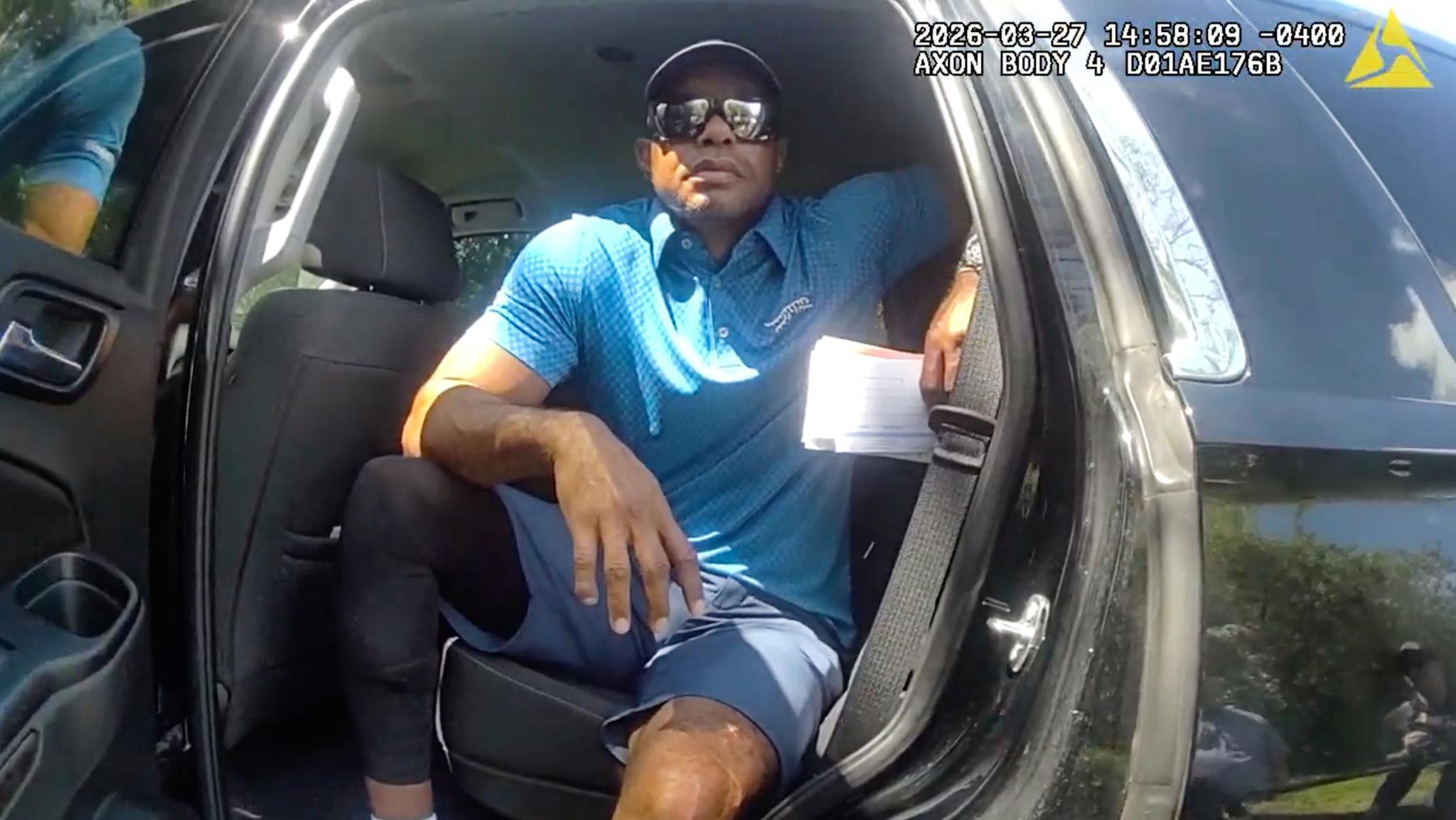 In this image from police body camera video released by the Martin County Sheriff's Office, golfer Tiger Woods sits in an unmarked police vehicle as he speaks with law enforcement personnel following a car crash in Jupiter Island, Fla., on Friday, March 27, 2026. 