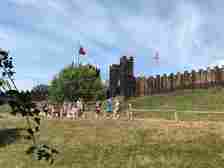 Essex castles: People walking in front of a wooden castle wall with battlements along the top