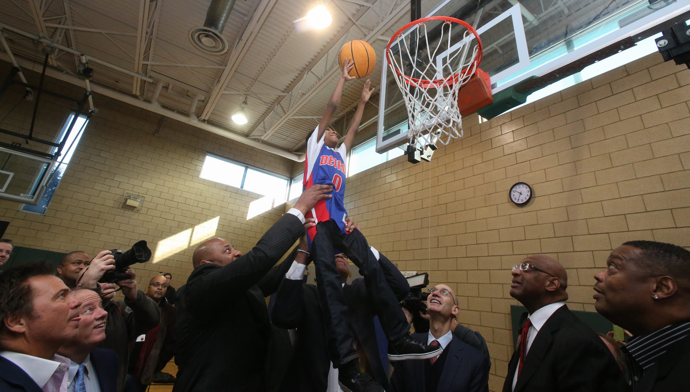 Former Detroit Pistons Earl Cureton and James Edwards lift Michael Willis for the ceramonial first dunk after the dedication of the new Detroit Pistons basketball court located in the SAY Detroit Play Center at Lipke Park in Detroit on Monday, Jan. 18, 2016.
