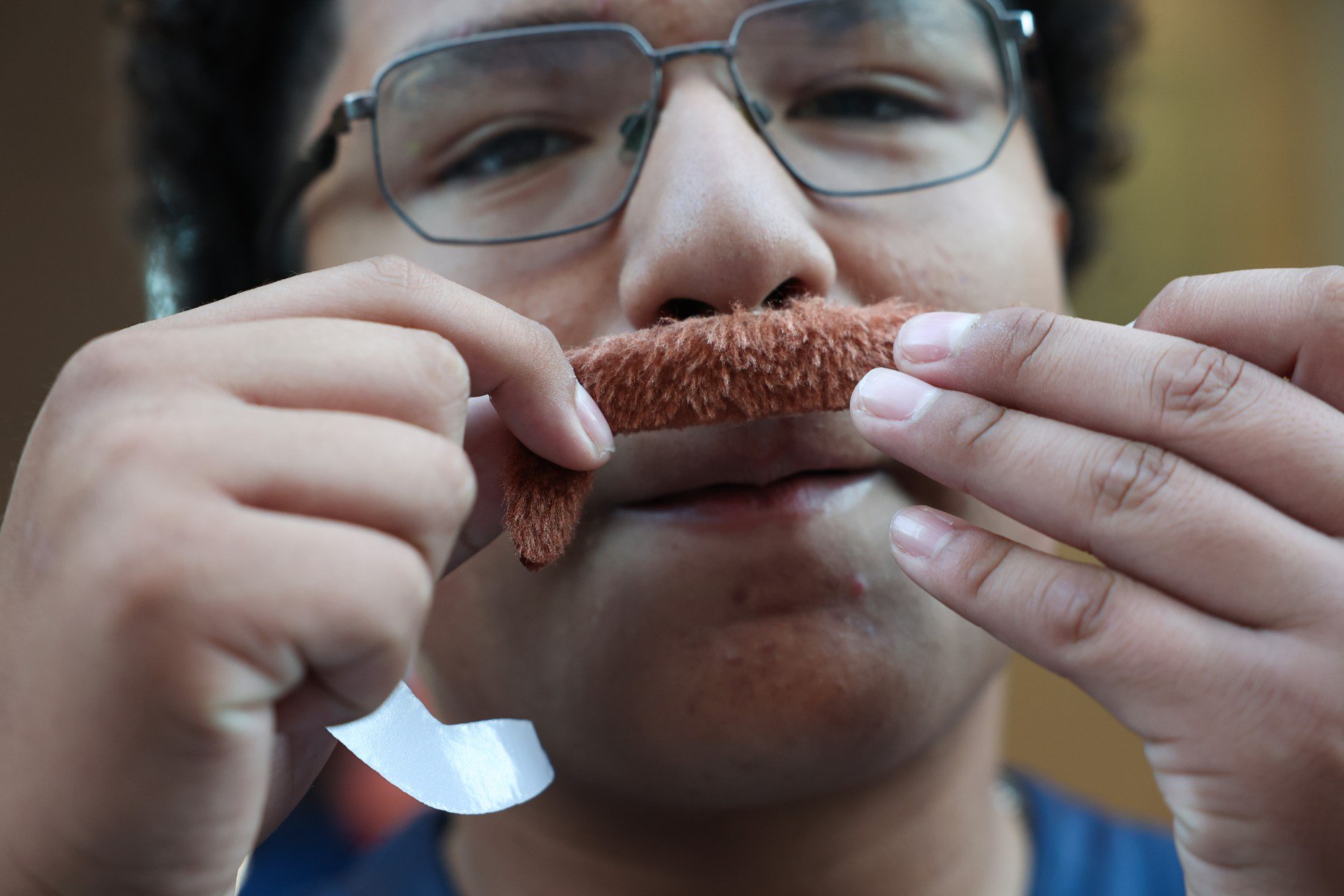 Andres Mascorro, 14, puts on a fake mustache resembling former Chicago Bears head coach and player Mike Ditka, given to fans at entry gates, before a Bears-Patriots game at Soldier Field on Oct. 22, 2026, in Chicago. (John J. Kim/Chicago Tribune)