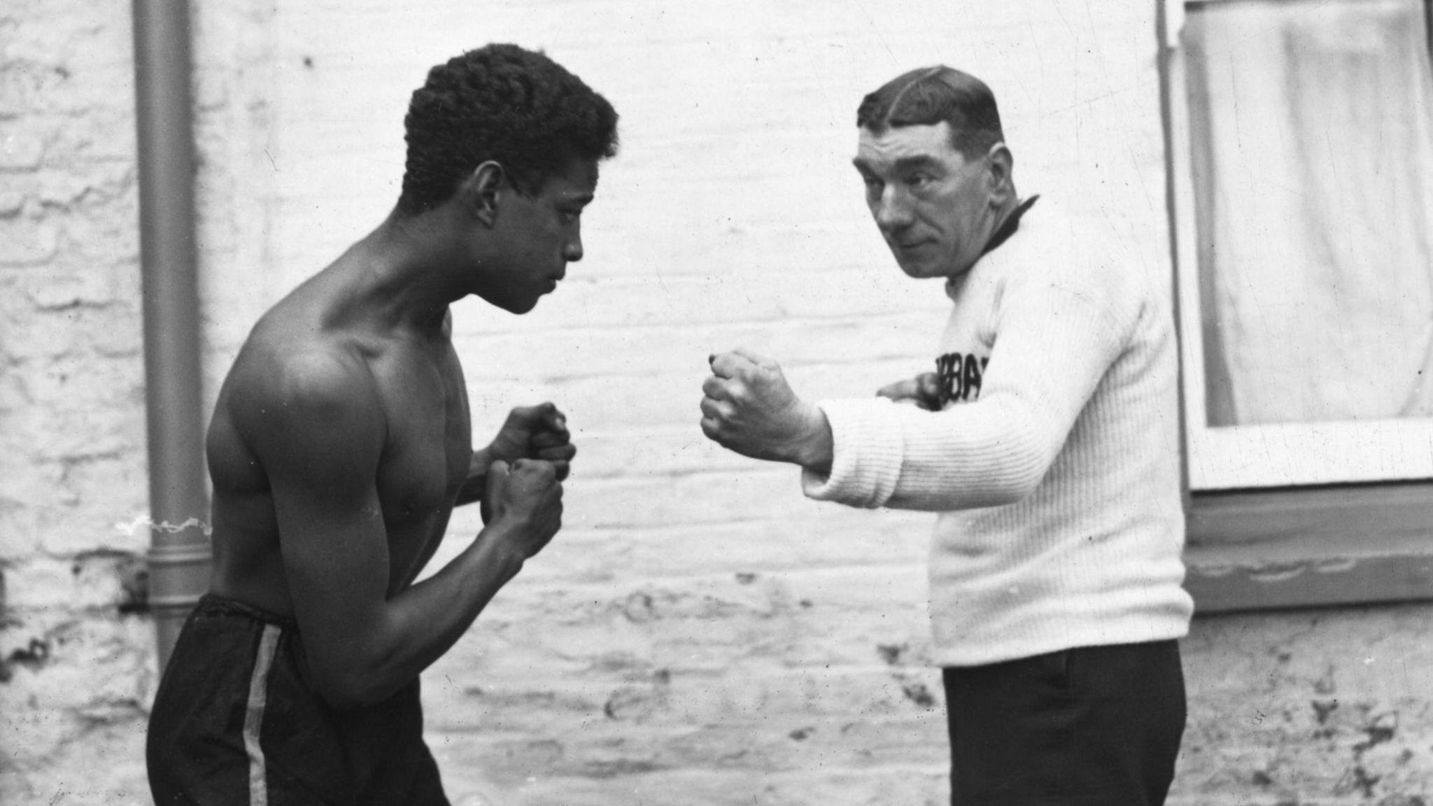 Johnson, wearing black shorts, sparring with his sparring partner, who wears a white jumper and black trousers.