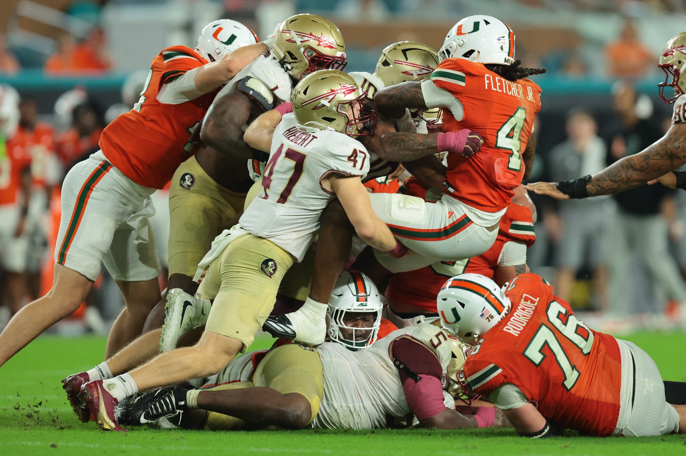 Oct 17, 2026; Miami Gardens, Florida, USA;  Miami Hurricanes running back Mark Fletcher Jr. (4) is tackled by Florida State Seminoles linebacker Chris Jones (10) and Florida State Seminoles defensive back Donny Hiebert (47) during the fourth quarter at Hard Rock Stadium.  Mandatory Credit: Sam Navarro-Imagn Images