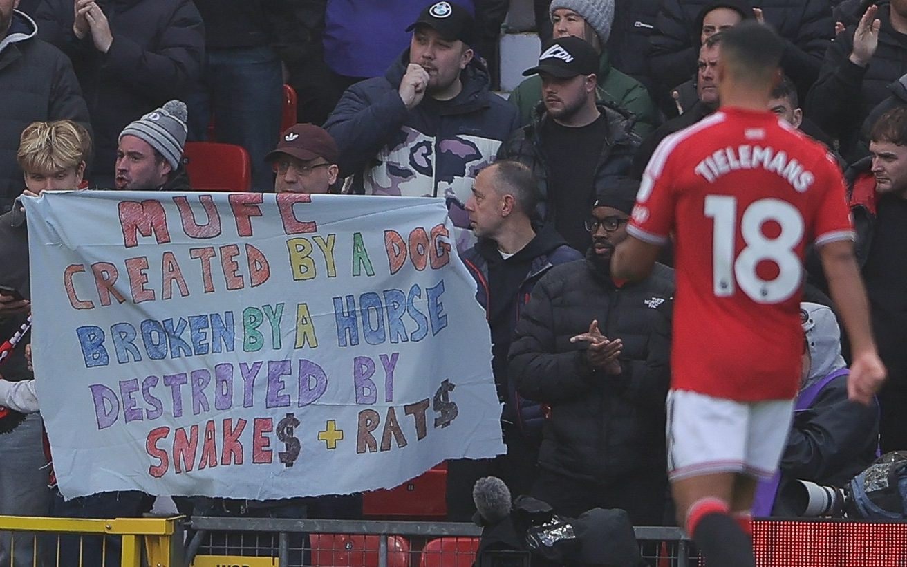 Manchester United fans lift up a banner in protest