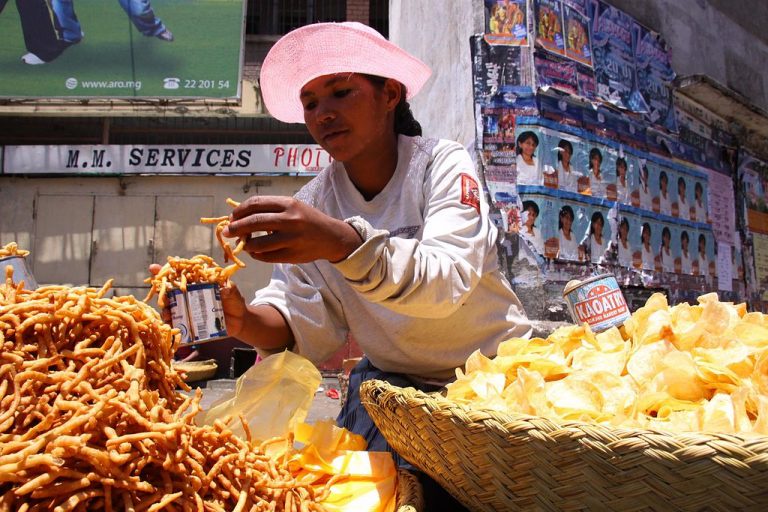 A Merina woman selling kaka pizon in Antananarivo, Madagascar. Photo source: Salym Fayad on Wikimedia Commons