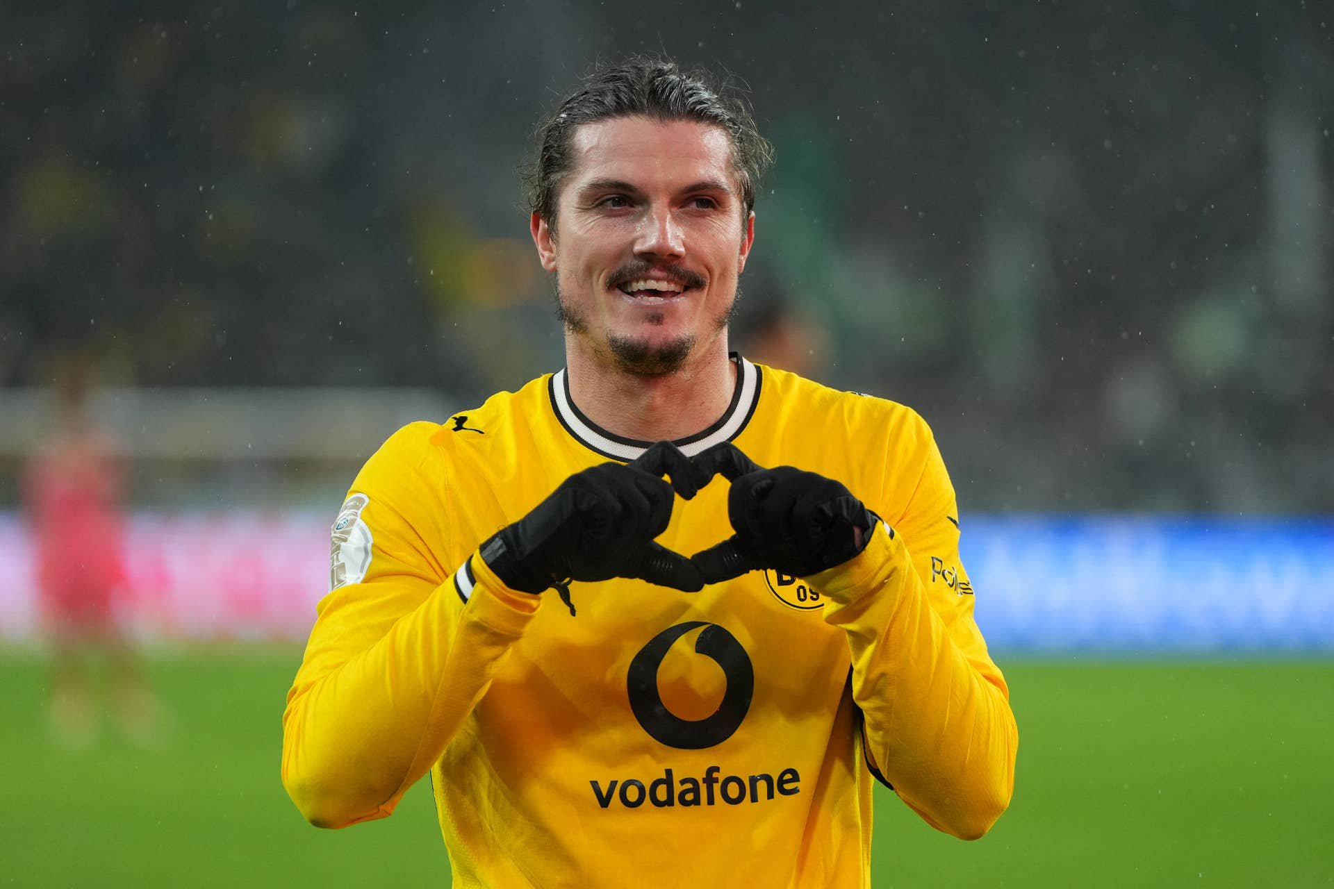 Ein Fußballspieler von Borussia Dortmund jubelt auf dem Spielfeld mit einem Herzzeichen.