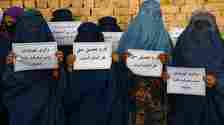 Getty  Afghan burqa-clad women hold placards as they protest for their right to education, in Mazar-i-Sharif on August 12, 2023. (