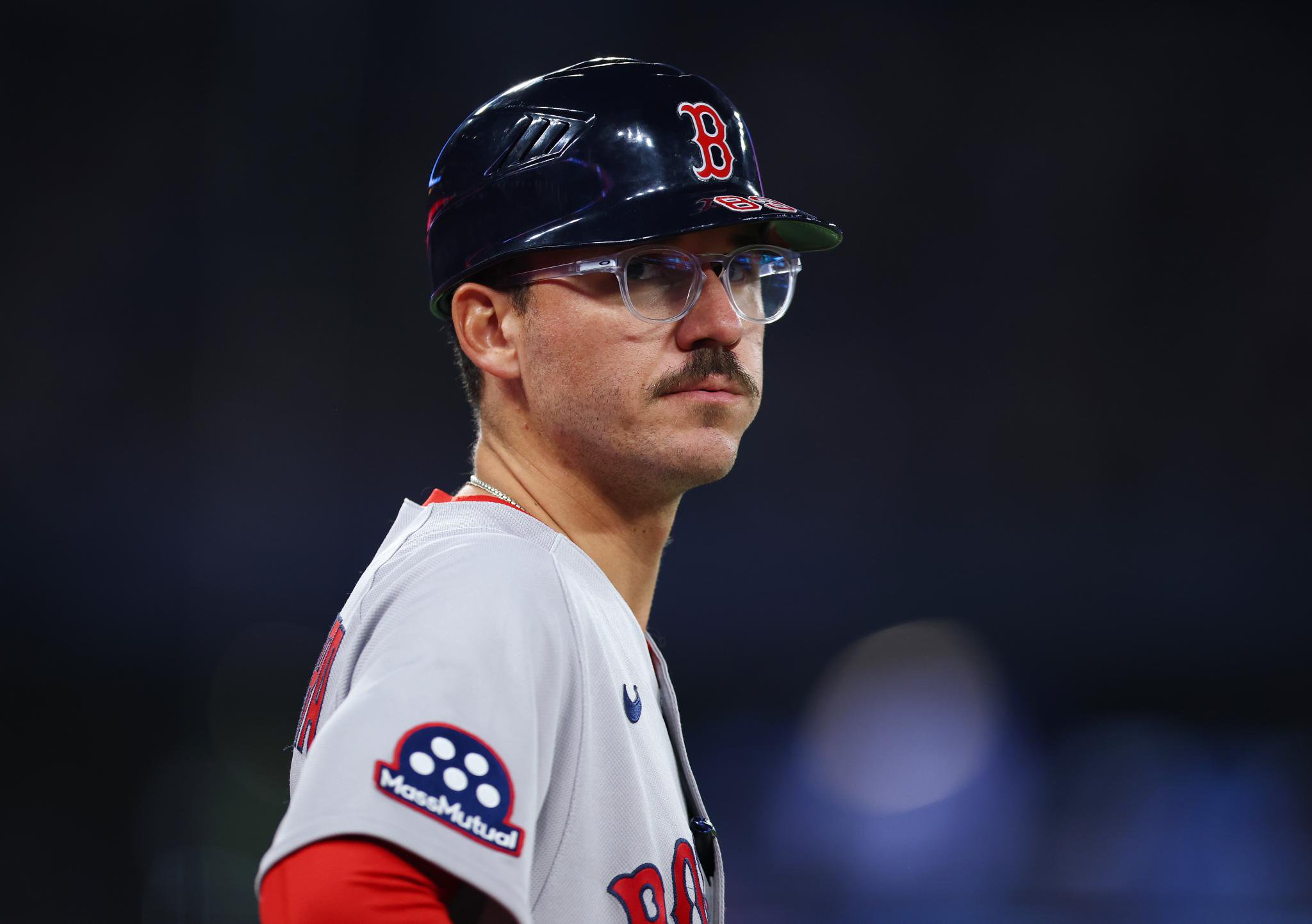 A close-up of a Boston Red Sox player wearing glasses and a batting helmet.