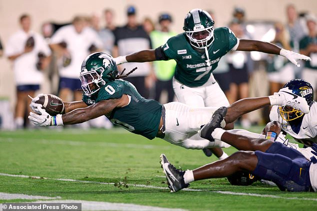 FILE - Michigan State running back Cam Edwards (0) dives over the goal line for a touchdown against Toledo linebacker Isaac Prince and Toledo defensive end Langston Long, bottom, as Michigan State running back Brandon Tullis (7) watches during an NCAA college football game, Sept. 4, 2026, in East Lansing, Mich. (AP Photo/Al Goldis, File)