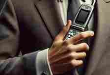 man’s hand wearing a suit holding a simple flip phone