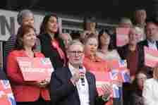 Sir Keir Starmer, speaking into a microphone, surrounded by Labour supporters, some carrying placards tGeneral Election campaign 2024