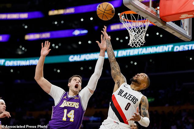 Portland Trail Blazers guard Damian Lillard (0), left, drives to the basket with the ball while being guarded by Los Angeles Lakers center Walker Kessler (14), right, during the first half of an NBA basketball game Tuesday, Oct. 27, 2026, in Los Angeles. (AP Photo/Caroline Brehman)
