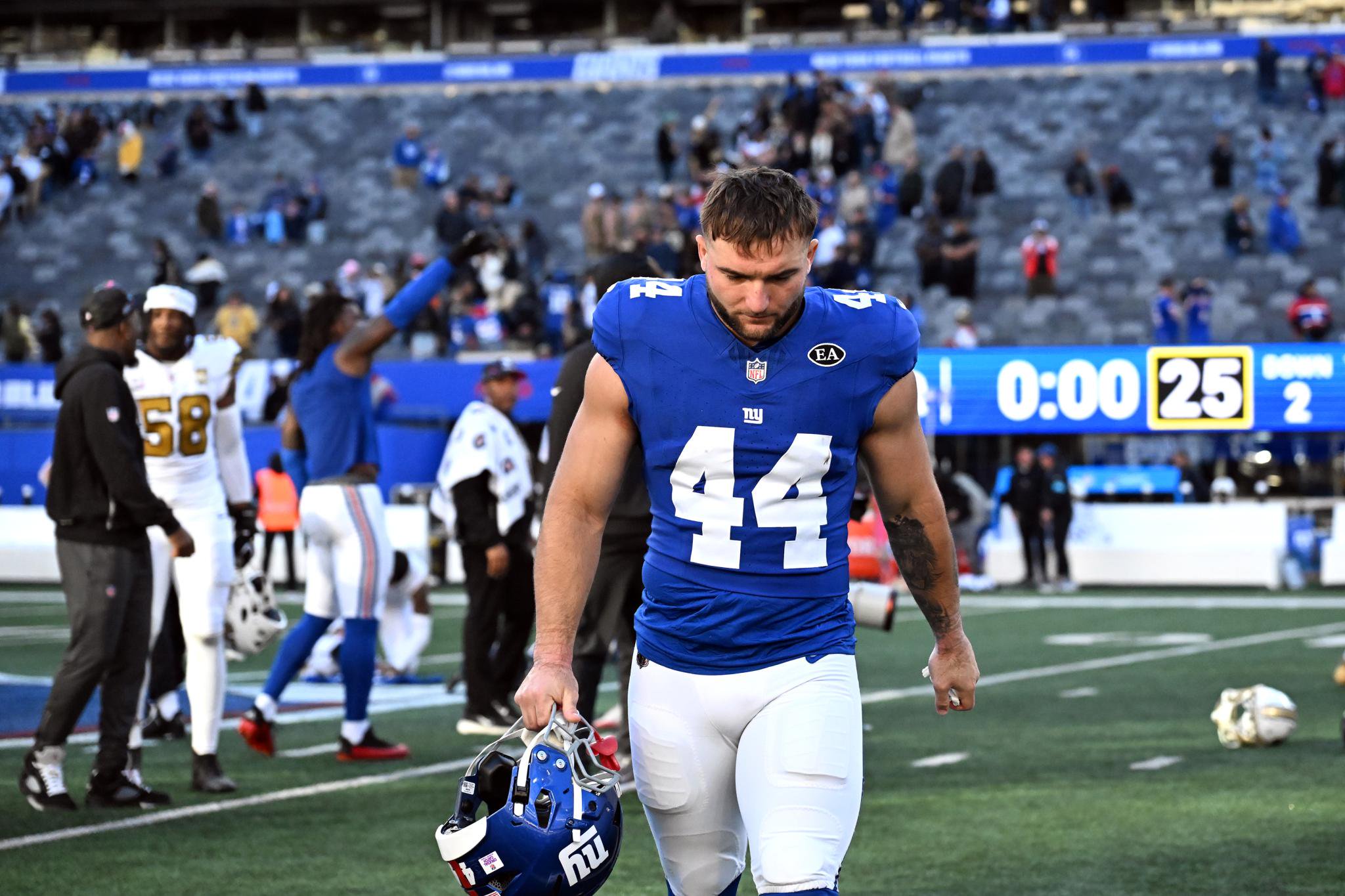 Giants running back Cam Skattebo (44) walks off the field holding his helmet.