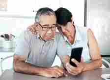 Shot of a senior couple looking unhappy while using a phone at home