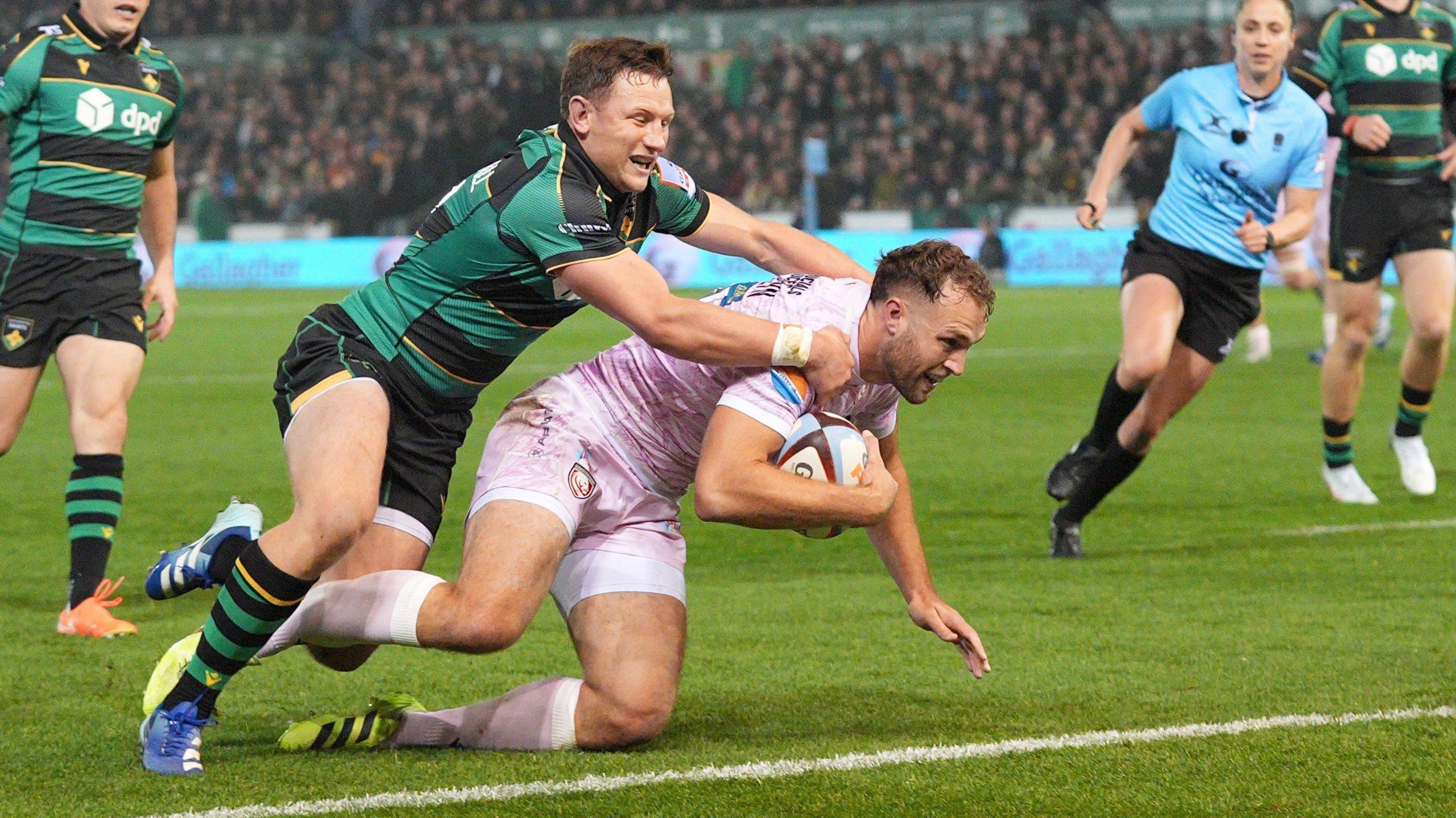 Max Llewellyn dives over the line to score for Gloucester, despite Fraser Dingwall's attempts to tackle him.
