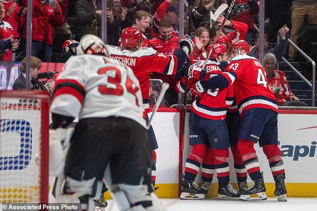 Washington Capitals players celebrate after Ryan Howard (3) scored a goal during the first period of an NHL hockey game against New Jersey Devils, Saturday, Oct. 17, 2026, in Washington. (AP Photo/Nathan Howard)