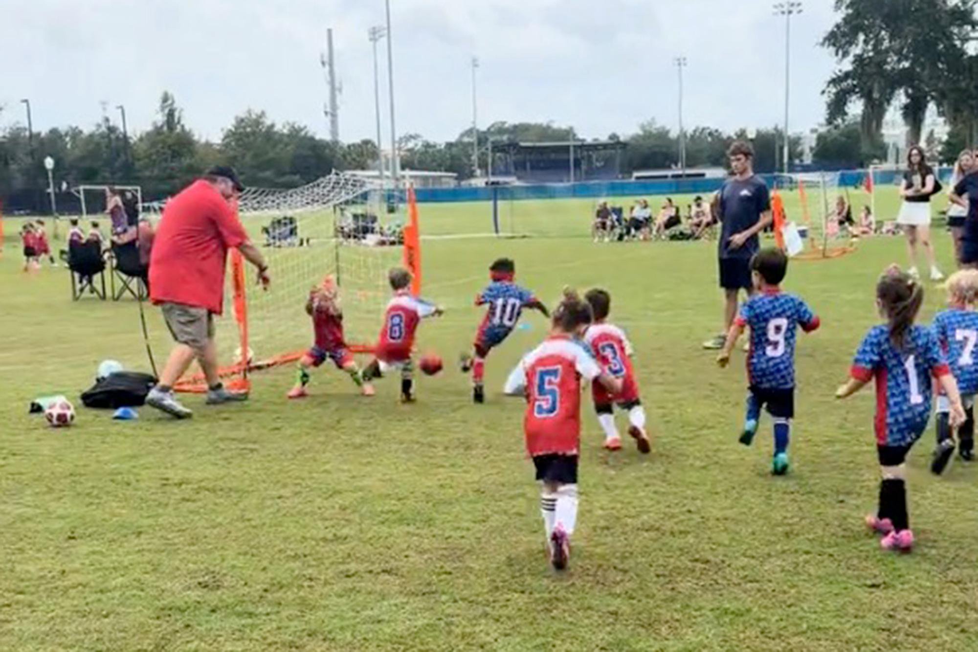 Young children play soccer on a field during a youth game.