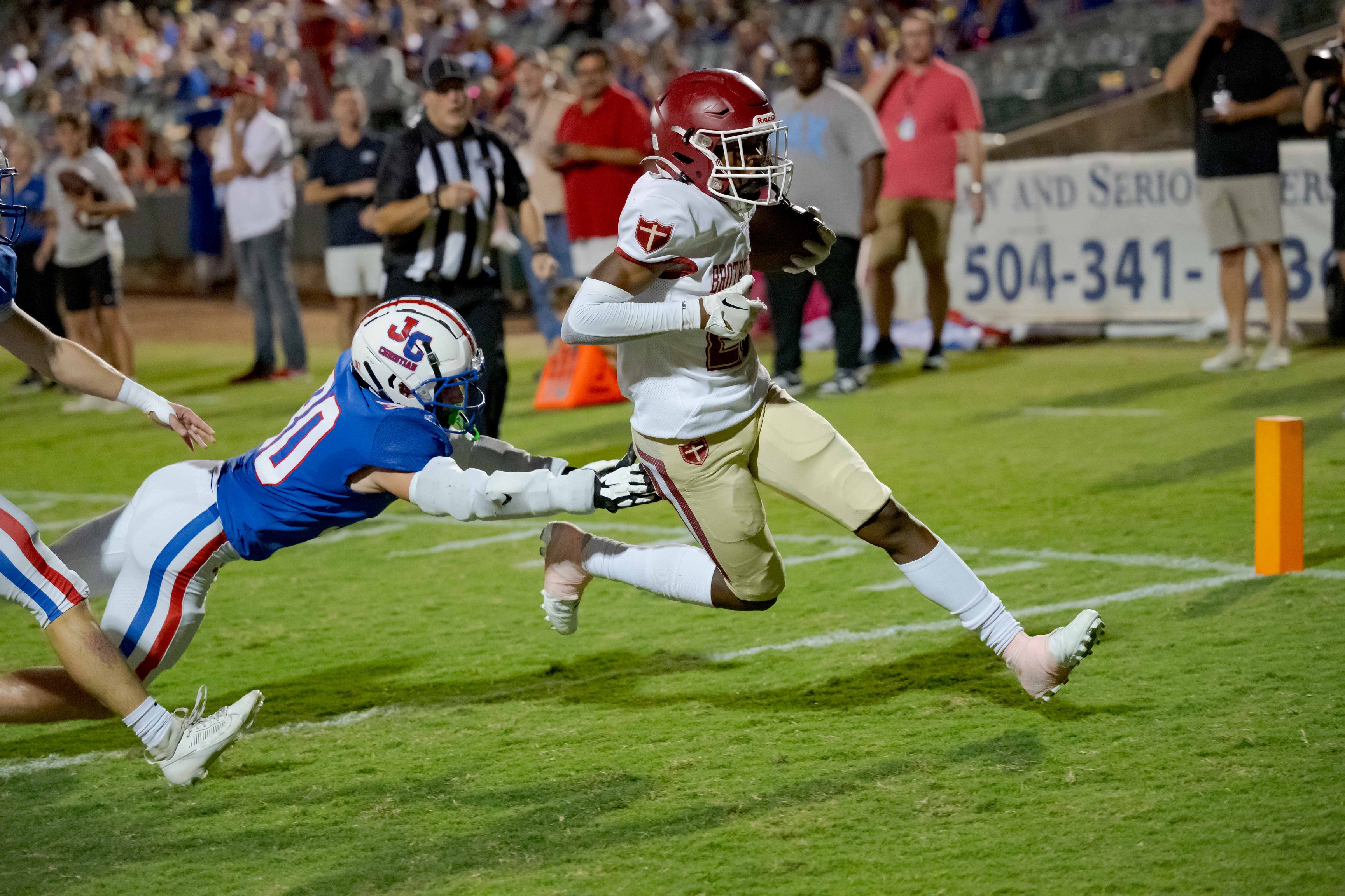 Brother Martin Crusaders wide receiver Easton Royal (23) scores a touchdown against John Curtis Patriots linebacker Benjamin Barron (30) during the first quarter at The Shrine on Airline. Mandatory Credit: Matthew Hinton-USA TODAY Sports